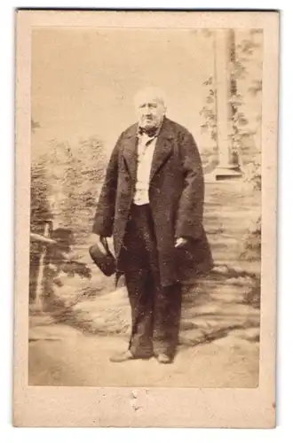 Fotografie unbekannter Fotograf und Ort, alter Herr im Anzug und Mantel mit Hut in der Hand