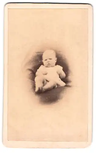 Fotografie unbekannter Fotograf und Ort, Baby im weissem Kleid auf einem Fell liegend