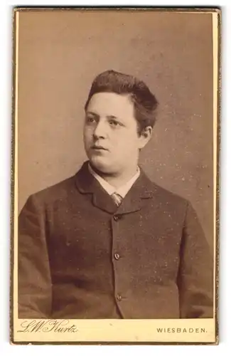 Fotografie L.W. Kurtz, Wiesbaden, Friedrichstrasse 4, Portrait eines jungen Mannes im dunklen Mantel