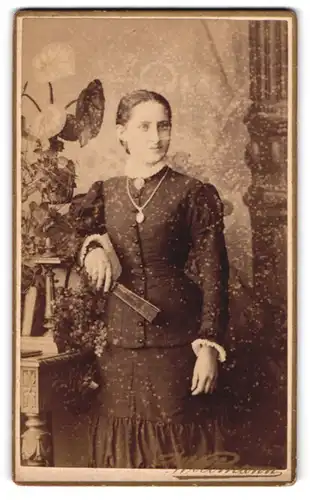 Fotografie C. Axtmann, Crimmitschau, streng blickende Dame mit tailliertem Kleid und Fächer