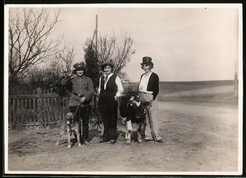 Fotografie Frauen tragen Faschings-Kostüm als Polizist mit Schäferhund, als Edelmann im Anzug & als Viehzüchter mit Kuh