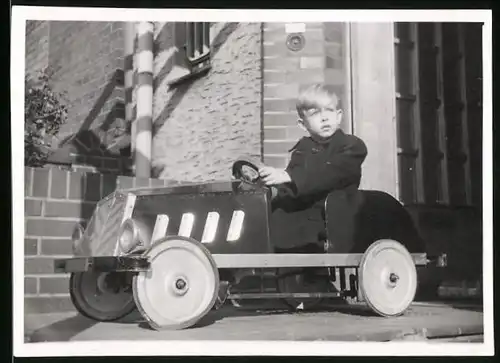 Fotografie blonder Knabe im Tretauto, Seifenkiste, Spielzeug-Auto