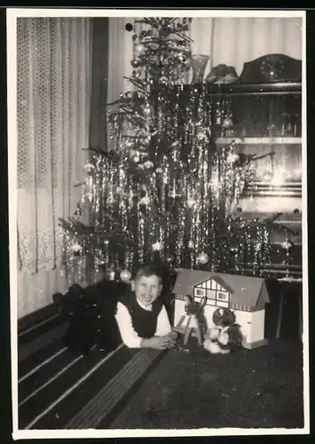 Fotografie Weihnachten, lachender Knabe mit Spielzeug unterm Weihnachtsbaum