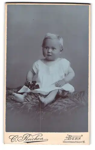 Fotografie C. Reichen, Bern, Waisenhausstrasse 16, niedliches Baby auf Fell mit Blume