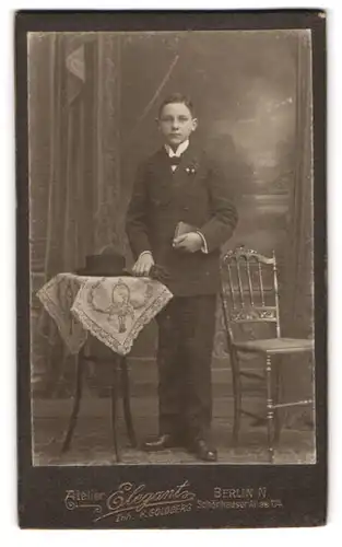 Fotografie Elegant, Berlin, Schönhauser Allee 114, junger Mann mit Gesangbuch am Tisch stehend