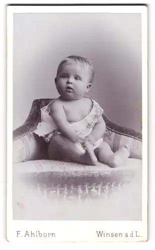 Fotografie F. Ahlborn, Winsen a.d.L., niedliches Baby auf einem Sofa sitzend