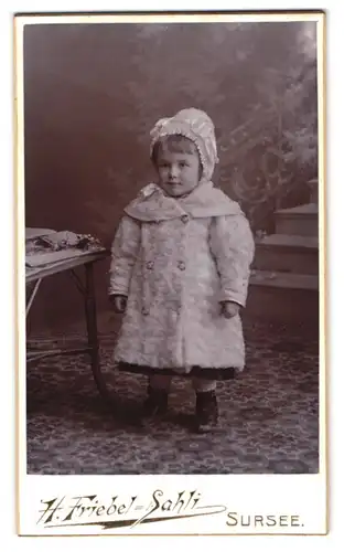 Fotografie H. Friebel-Sahli, Sursee, kleines Mädchen in Mantel und mit Haube