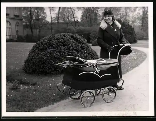 Fotografie Mutterglück, lächelnde Mutter schaut in den Kinderwagen