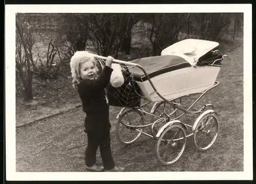 Fotografie kleines Mädchen schiebt ihren Kinderwagen