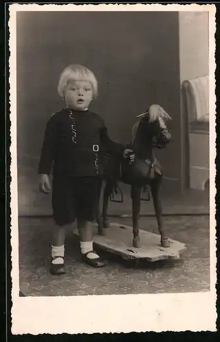 Fotografie Blonder Knabe mit Spielzeug-Pferd