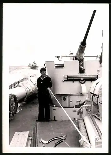 Fotografie Bundesmarine, Matrose auf einem Kriegsschiff neben Geschütz stehend