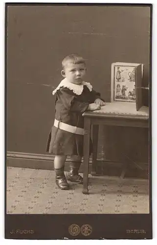 Fotografie J. Fuchs, Berlin, Friedrichstrasse 108 u. 138, Kleines Kind im Kleid mit Bilderbuch