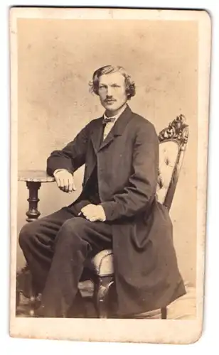 Fotografie Albert Grundner, Berlin, Herr im Anzug mit Fliege sitzend am Tisch