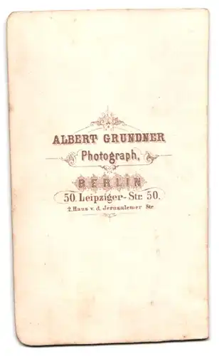 Fotografie Albert Grundner, Berlin, Herr im Anzug mit Fliege sitzend am Tisch