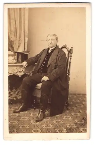 Fotografie G. Wünsch, Wien, Portrait älterer Herr im Anzug mit Mantel und Zylinder auf dem Tisch
