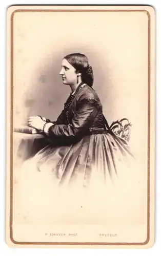 Fotografie P. Schiffer, Crefeld, junge Frau im seidenen Kleid mit Ohrringen und Perlenkette