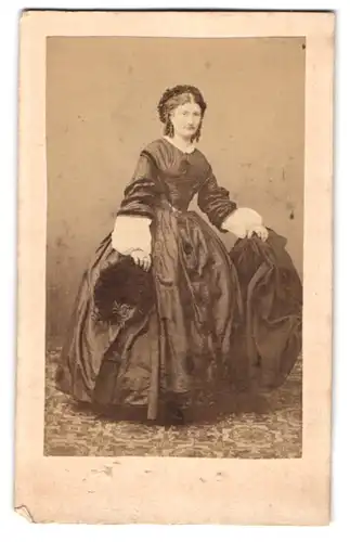 Fotografie unbekannter Fotograf und Ort, Portrait junge Frau im dunklen seidenen Kleid mit Hut in der Hand