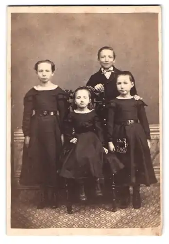 Fotografie unbekannter Fotograf und Ort, Portrait vier junge Kinder in schwarzen Kleidern und im Anzug