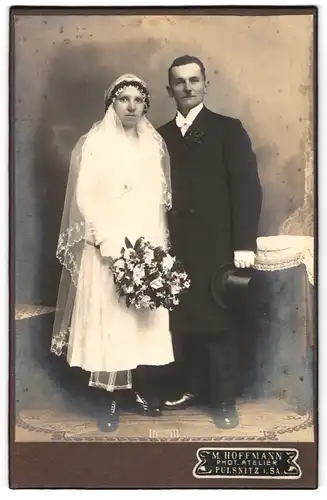 Fotografie M. Hoffmann, Pulsnitz i. Sa., Eheleute im weissen Hochzeitskleid und im schwarzen Anzug mit Zylinder