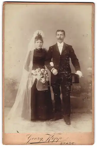 Fotografie Georg Kopp, Stade, Hochzeitspaar im schwarzen Kleid mit weissen Schleier und im Anzug mit Zylinder