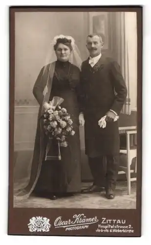 Fotografie Oscar Krämer, Zittau, Ehepaar im schwarzen Hochzeitskleid und im Anzug mit Brautstrauss