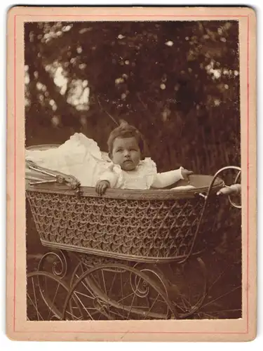 Fotografie unbekannter Fotograf und Ort, Portrait niedliches Kleinkind schaut aus dem Kinderwagen heraus, 1909