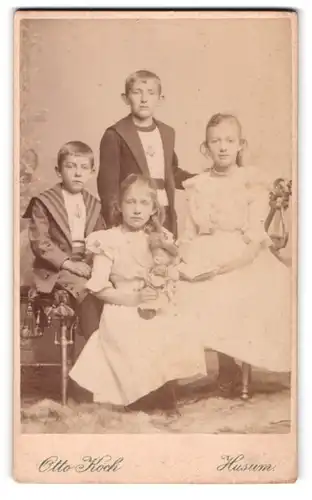 Fotografie Otto Koch, Husum, zwei Mädchen und Knaben in Anzügen und Kleidern mit Puppe im Arm