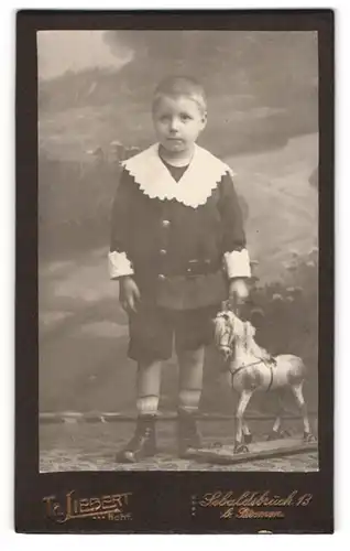 Fotografie Th. Liebert, Bremen, junger Knabe im Anzug mit Spielzeug Pferd