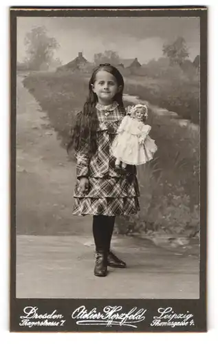 Fotografie Atelier Herzfeld, Dresden, niedliches Mädchen im karierten Kleid mit ihrer Puppe im Arm