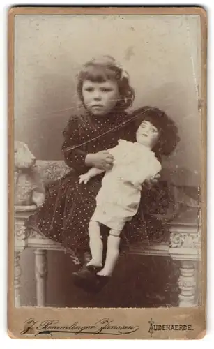 Fotografie J. Remmlinger Janssen, Audenaerde, kleines Mädchen im Pünktchenkleid mit grosser Puppe im Arm