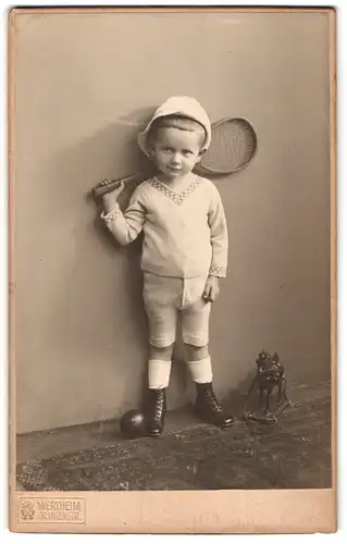 Fotografie Wertheim, Berlin, kleiner Knabe in kurzen Stumpfhosen mit Tennisschläger und Spielzeug Pferd