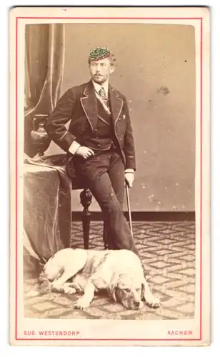 Fotografie Eug. Westendorp, Aachen, Student im Anzug mit Couleur und Biertönnchen samt seinem Hund im Atelier