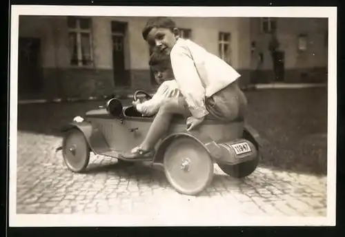 Fotografie Knaben fahren gemeinsam mit Tretauto, Spielzeug-Auto, Seifenkiste