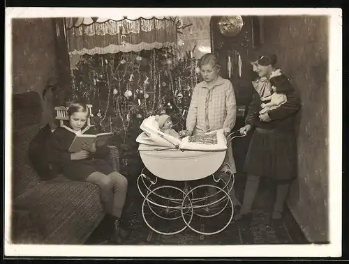 Fotografie Weihnachten, glückliche Mädchen mit Puppe & Puppenwagen vor Weihnachtsbaum