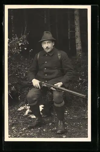 Foto-AK Jäger mit Gewehr auf einem Hocker im Wald