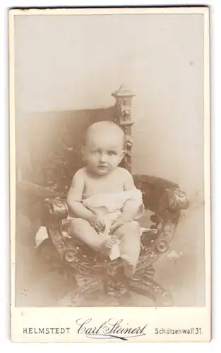 Fotografie Carl Steinert, Helmstedt, Schützenwall 31, Schüchtern blickendes Baby auf einem Sitzmöbel