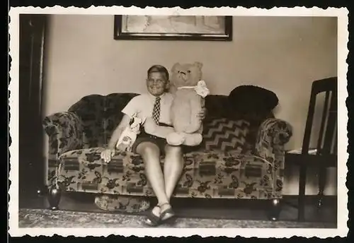 Fotografie Knabe mit Teddybär / Teddy auf Sofa sitzend