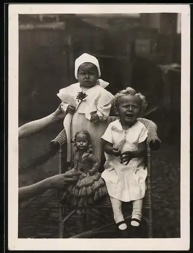 Fotografie Spielzeug, weinendes Mädchen bekommt eine Puppe gereicht