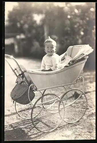 Fotografie lachendes Baby im Kinderwagen sitzend