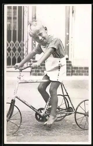 Fotografie blonder Knabe fährt mit altem Dreirad - Fahrrad