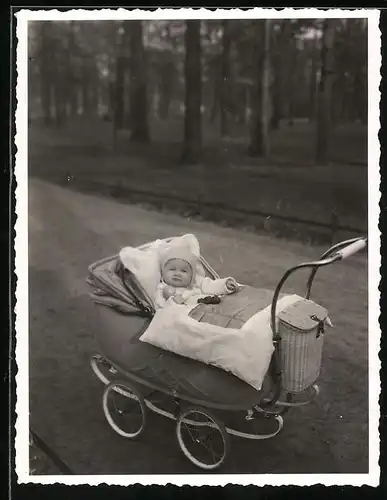 Fotografie Baby mit Rassel im Kinderwagen liegend