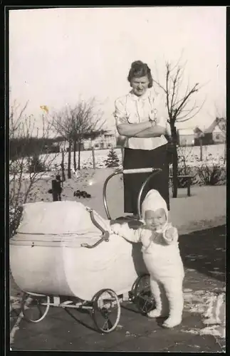 Fotografie Mutterglück, Mutter nebst stehendem Baby am Kinderwagen