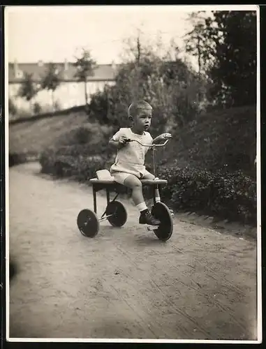 Fotografie Knabe fährt konzentriert auf seinem Dreirad