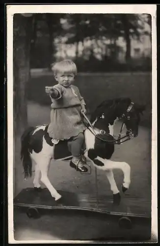 Fotografie Kleinkind auf Spielzeug-Pferd sitzend
