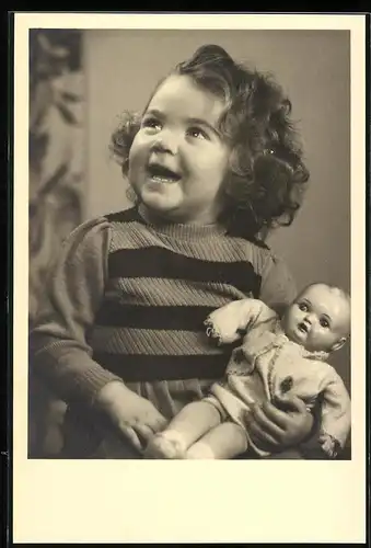 Fotografie Spielzeug, lachendes Mädchen mit Puppe im Arm