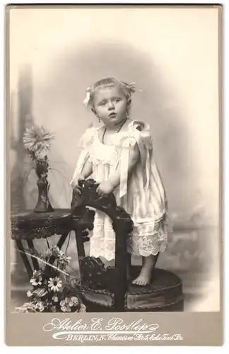 Fotografie E. Postlep, Berlin, Portrait niedliches kleines Mädchen im weissen Kleidchen mit Haarschleifen