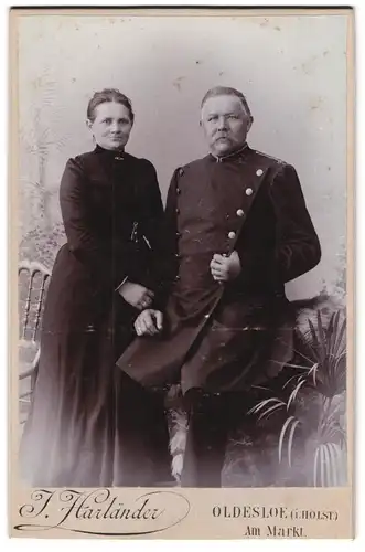 Fotografie J. Hartländer, Oldesloe i. Holst., älterer Eisenbahner in Uniform nebst seiner Frau im Atelier