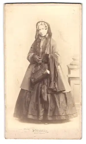 Fotografie Buchner, Stuttgart, ältere Lady Whateley im Winterkleid mit Handtasche und Pelzschal