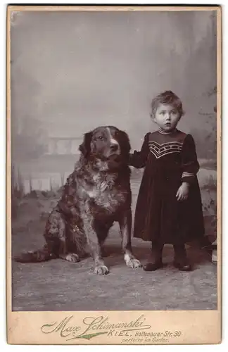 Fotografie Max Schimanski, Kiel, kleines Mädchen Grete im Samtkleid mit ihrem grossen Hund bei Fuss im Atelier