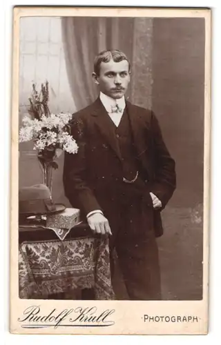 Fotografie Rudolf Krull, Ort unbekannt, Junger Herr im Anzug mit Fliege